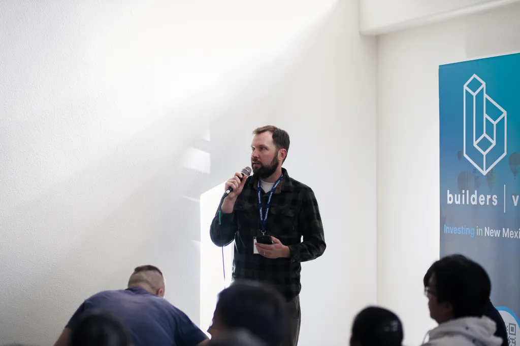 Speaker presenting near the builders vc banner at Desert Dev Lab 2025