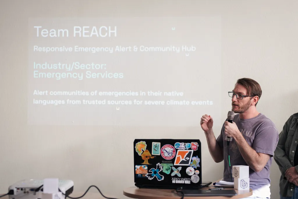 Presenter speaking on Team REACH's emergency alert project at Desert Dev Lab 2025