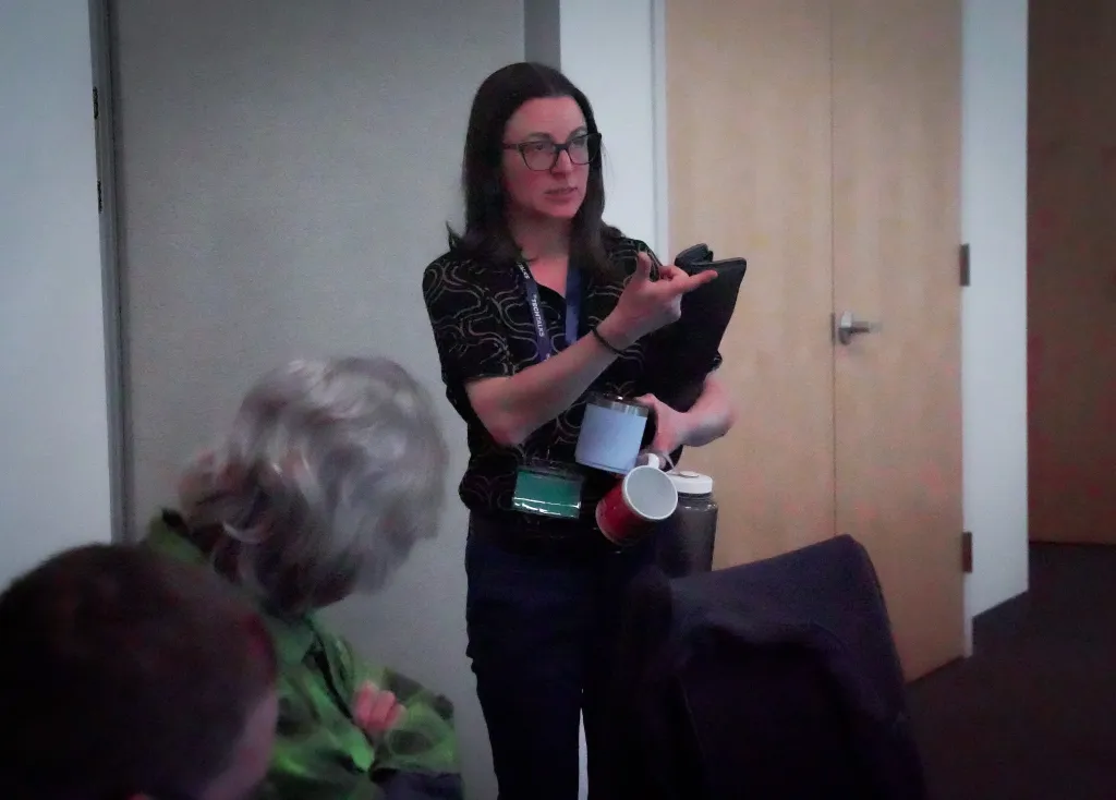 Attendee speaking while holding a notebook and travel mug at Desert Dev Lab 2026