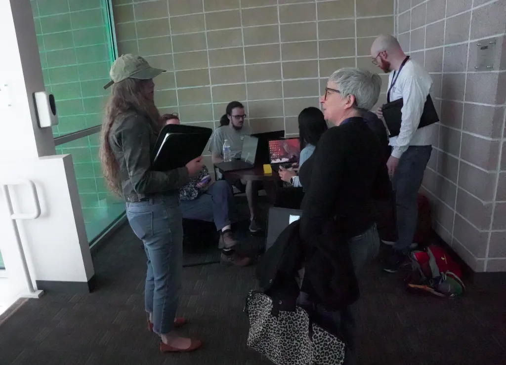 Small group of attendees chatting near a tiled wall at Desert Dev Lab 2026